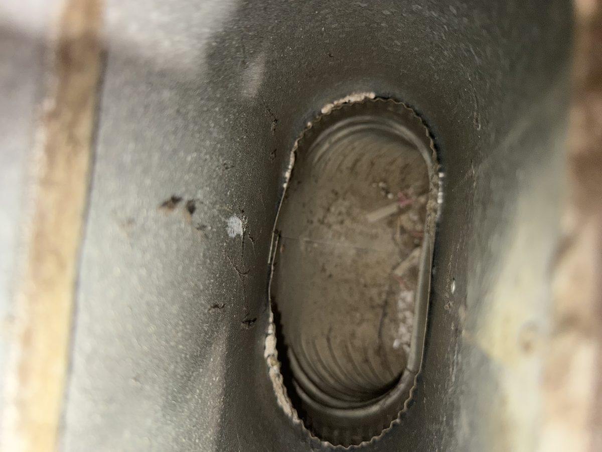 Debris lying inside an oval duct where it leaves the register boot